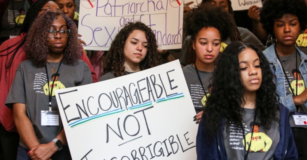 Young women from Girls for Gender Equity hold signs, one of which reads: Encourageable not Incorrigible